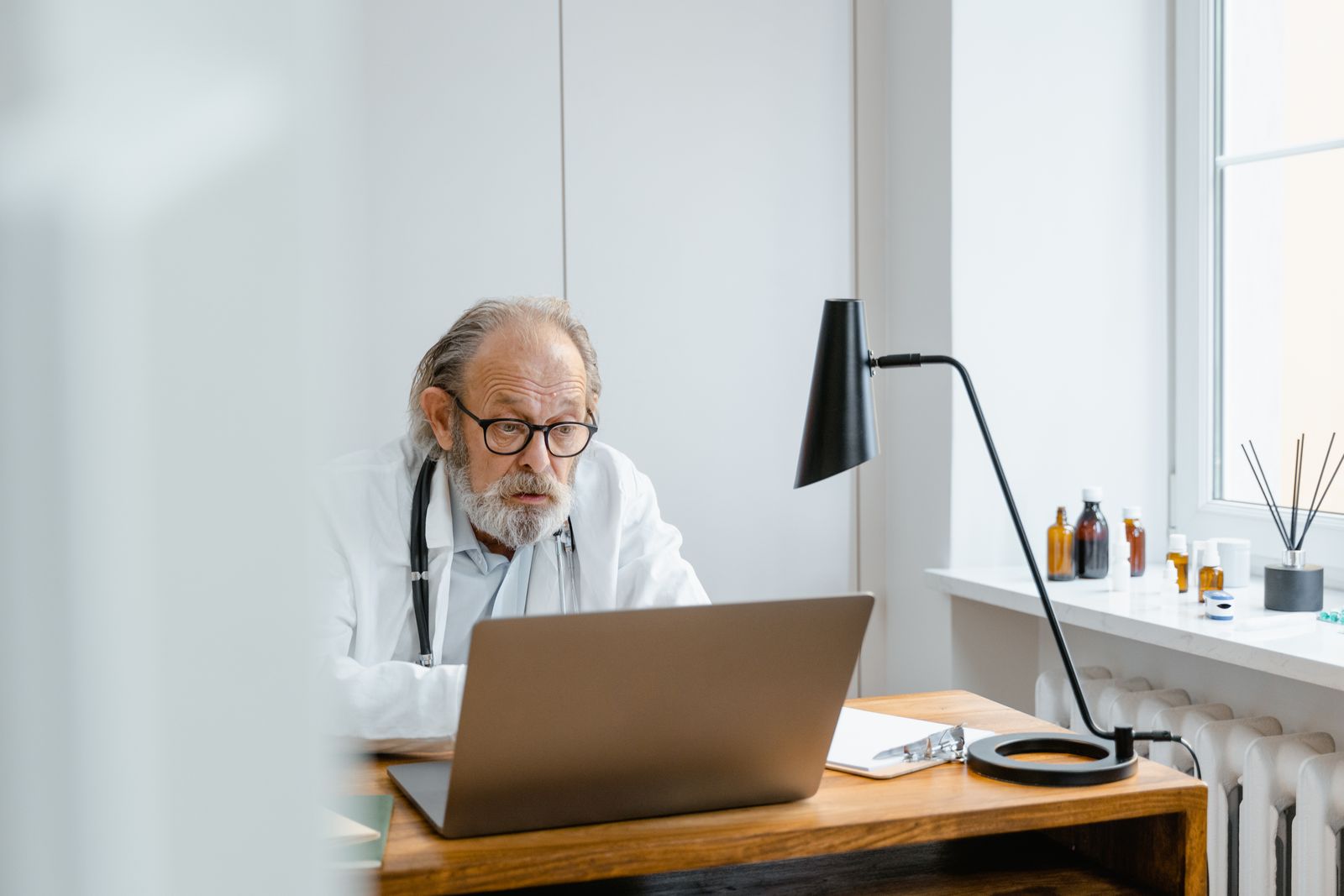 Doctor reviewing notes on a laptop at a desk in a clinic office